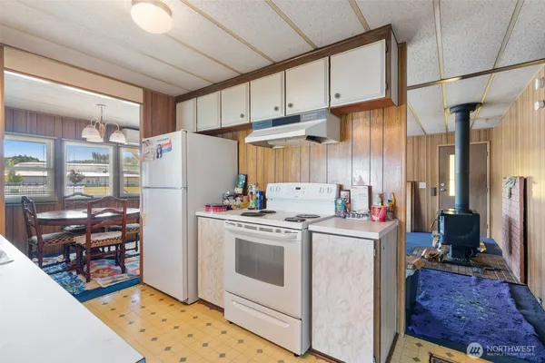 a kitchen with stainless steel appliances a stove a refrigerator a sink a dining table and chairs with wooden floor