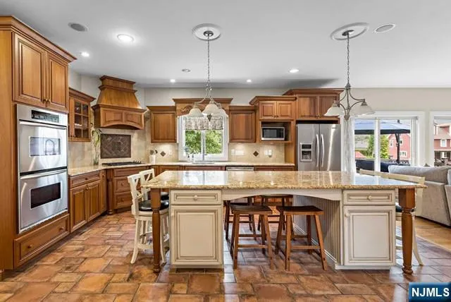 a kitchen with stainless steel appliances granite countertop a stove a sink a oven a refrigerator and chairs