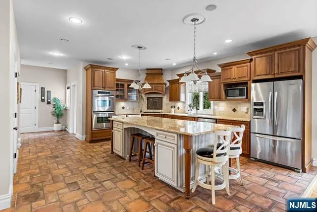 a kitchen with stainless steel appliances granite countertop a refrigerator a stove top oven a sink dishwasher and a refrigerator