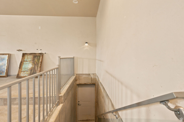 580 North 300 East Logan, UT 84321 - Photo 37 of 74 Staircase featuring light-toned walls, metal railings, and an enclosed doorway