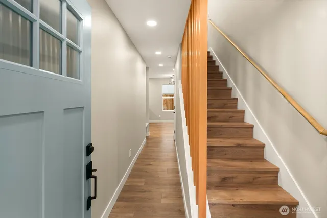 a view of a hallway with wooden floor and stairs
