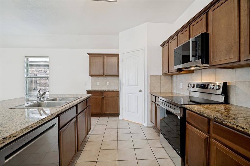 3415 Emerson Road Forney, TX 75126 - Photo 8 of 26 a kitchen with stainless steel appliances granite countertop a sink stove and microwave