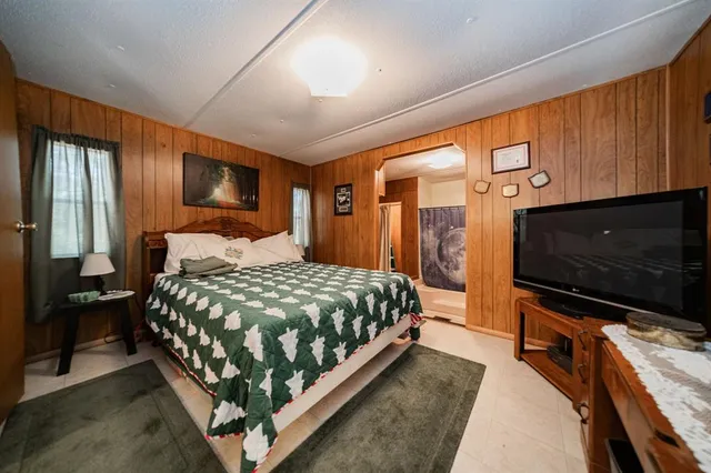 a bedroom with a bed television on desk and a window