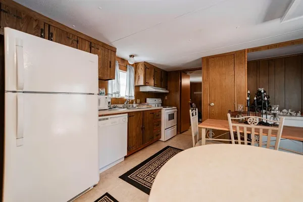 a kitchen with a refrigerator a stove a sink a dining table and chairs