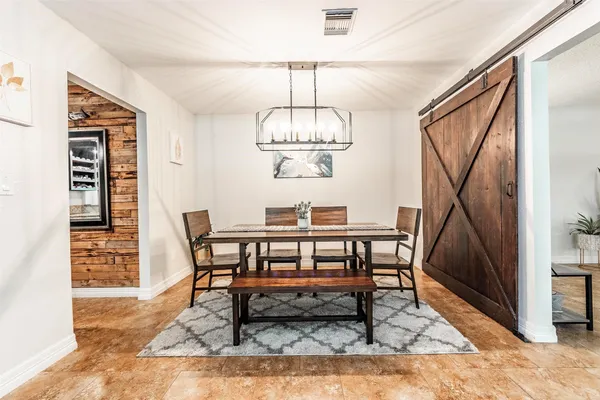 a dining room with wooden floor a chandelier a wooden table and chairs