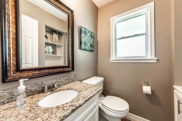 a bathroom with a granite countertop toilet a sink and a mirror