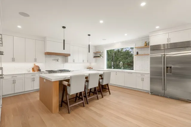 a large kitchen with kitchen island a large counter space appliances and a living room view