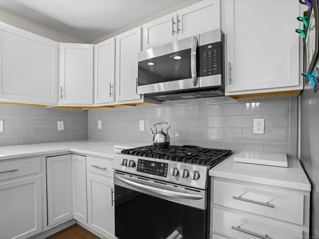 a kitchen with stainless steel appliances granite countertop white cabinets and a stove a oven with white countertops