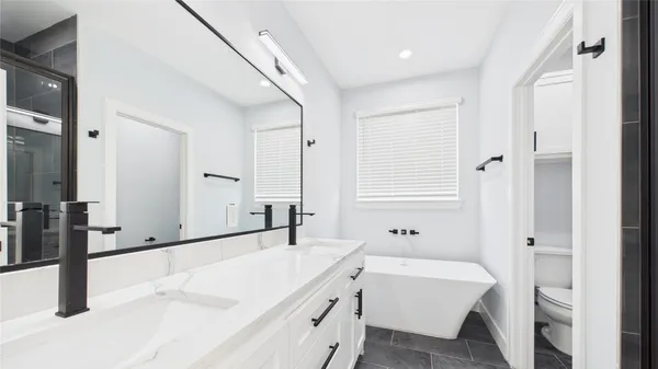a bathroom with a granite countertop sink and a bathtub