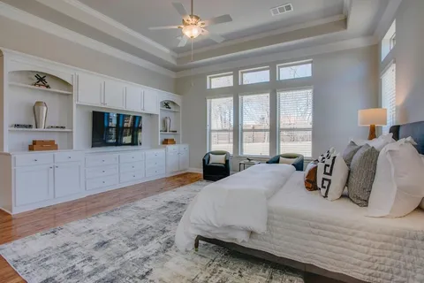 a bedroom with a large bed and a flat tv screen on dresser