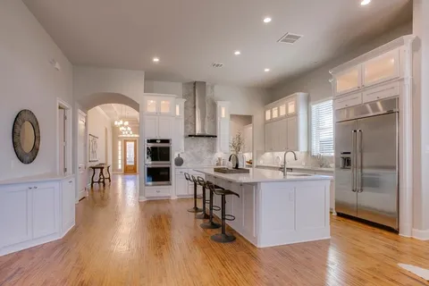 a kitchen with stainless steel appliances granite countertop a stove top oven a refrigerator a sink and a dining table with wooden floor