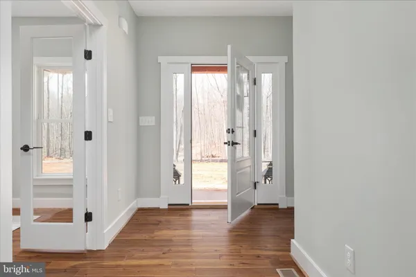 a view of an empty room with wooden floor and a window