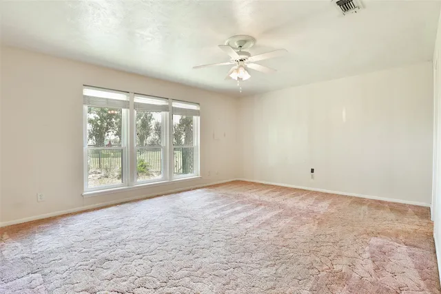 a view of an empty room with chandelier fan and fire place