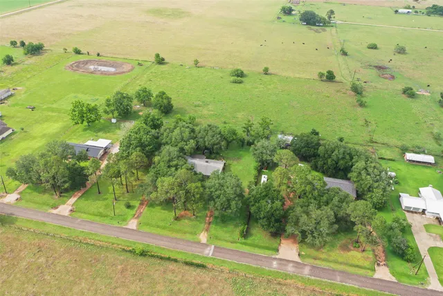 an aerial view of residential houses with outdoor space and trees