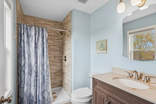 a bathroom with a sink a toilet a shower and a mirror