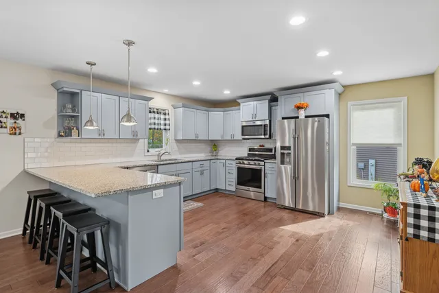 a kitchen with stainless steel appliances granite countertop a refrigerator a sink dishwasher a stove and a refrigerator with wooden floor