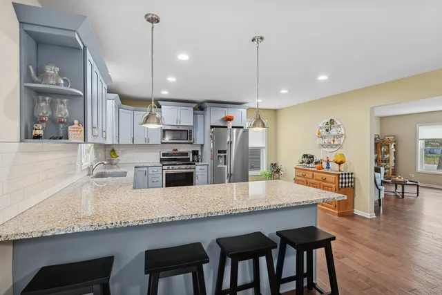 a kitchen with granite countertop a table chairs stainless steel appliances and wooden floor