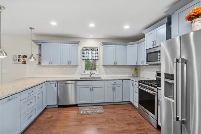 a kitchen with stainless steel appliances granite countertop a stove top oven a sink and dishwasher a refrigerator with white cabinets