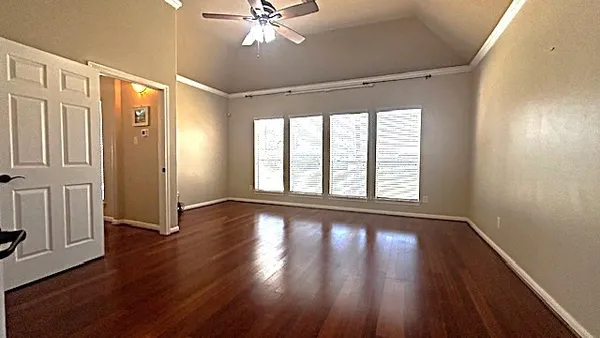 a view of an empty room with wooden floor and a window
