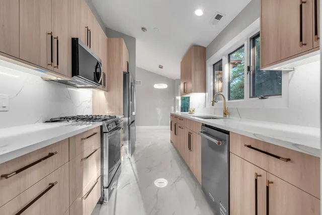 a kitchen with stainless steel appliances granite countertop a sink a stove and a refrigerator