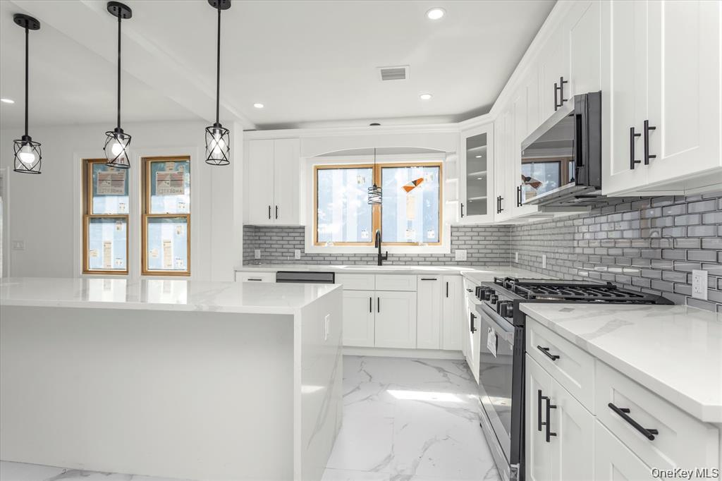 44 School Street Malverne, NY 11565 - Photo 8 of 19 a kitchen with stainless steel appliances granite countertop a sink a stove a refrigerator and white cabinets