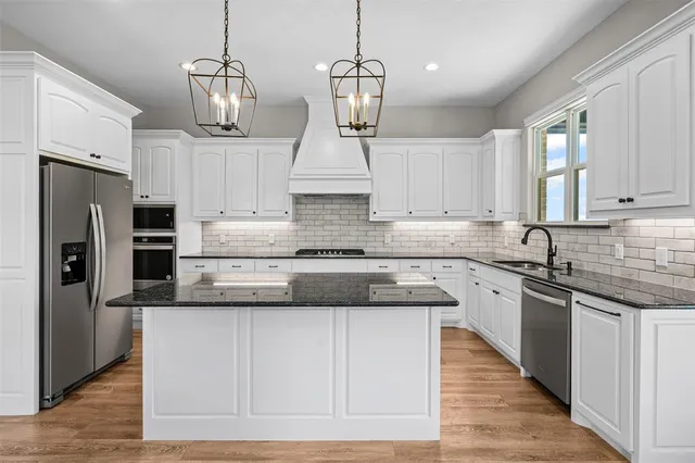 a kitchen with granite countertop a sink dishwasher and white cabinets with wooden floor