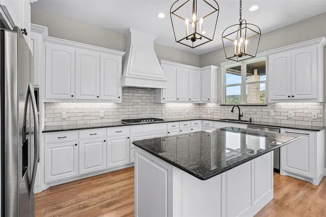 a kitchen with granite countertop stainless steel appliances sink cabinets and window