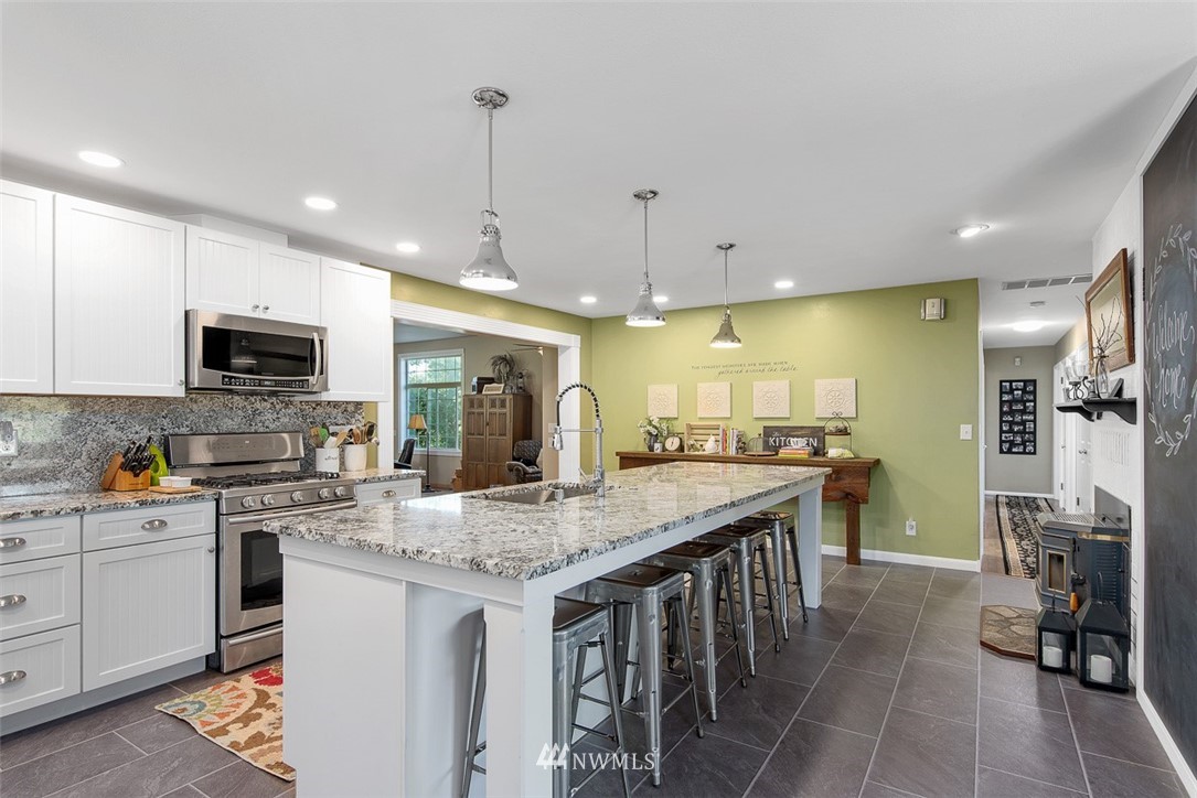5495 Sand Road Bellingham, WA 98226 - Photo 9 of 40 a kitchen with stainless steel appliances granite countertop a stove top oven a sink dishwasher a dining table and chairs with wooden floor