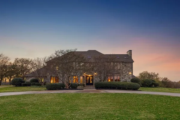 a view of a big house with a big yard and large trees
