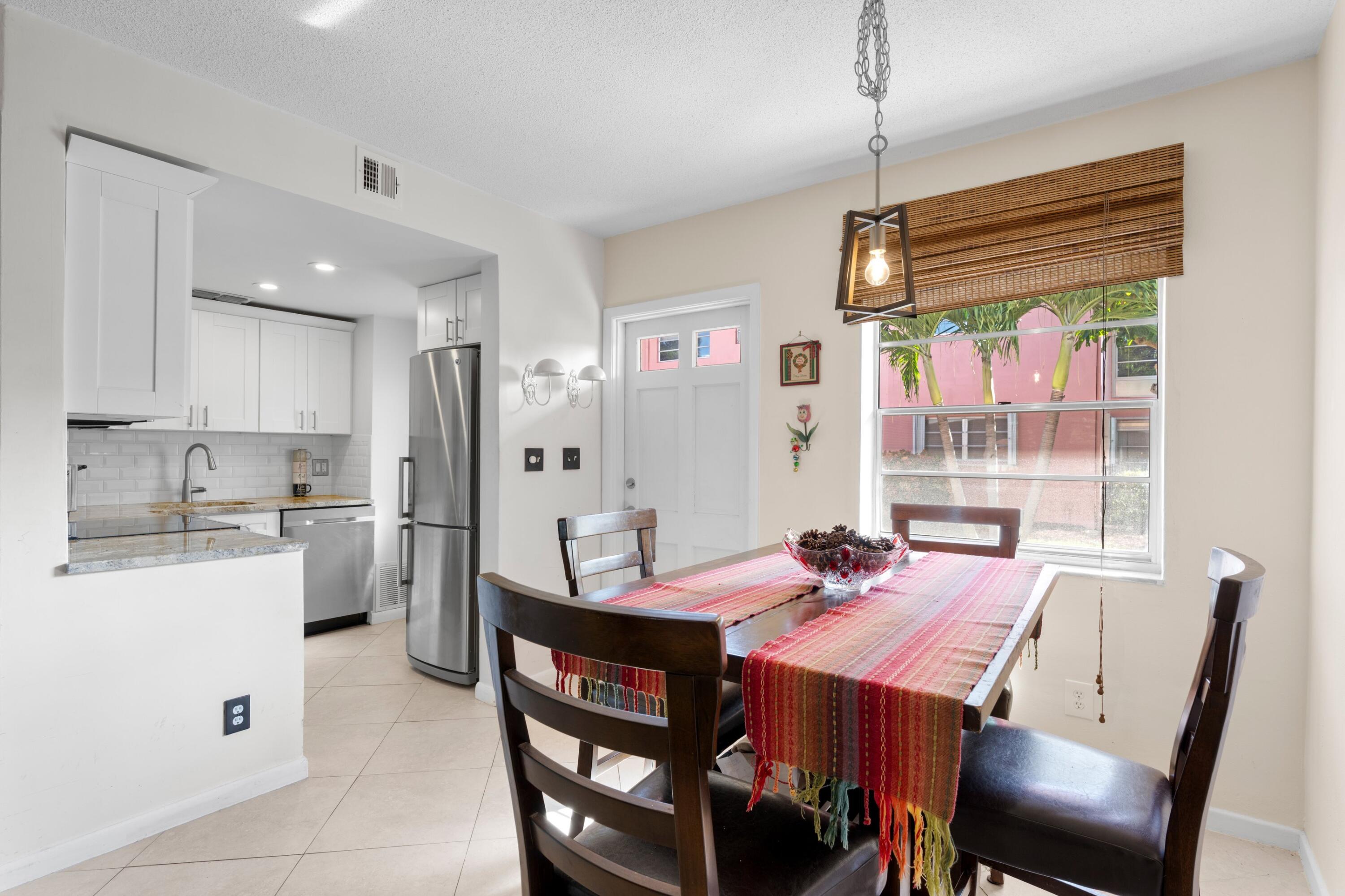 300 Northeast 20th Street, Unit 109 Boca Raton, FL 33431 - Photo 7 of 36 a kitchen with a dining table chairs and refrigerator