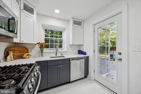 a kitchen with a sink a stove a window and cabinets