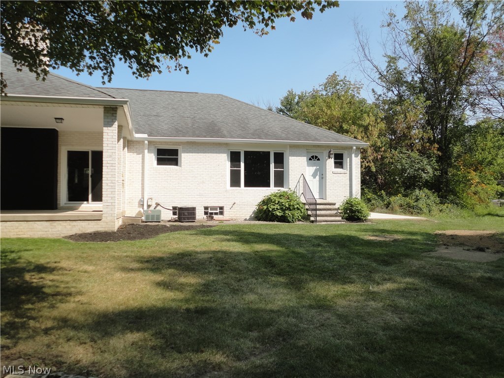 19646 Prospect Road Strongsville, OH 44149 - Photo 28 of 32 Covered patio to left side, two a/c units, back entrance to laundry room and concrete parking pad to right of house.
