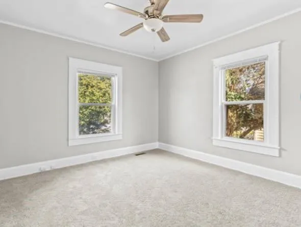 an empty room with a window and a fan