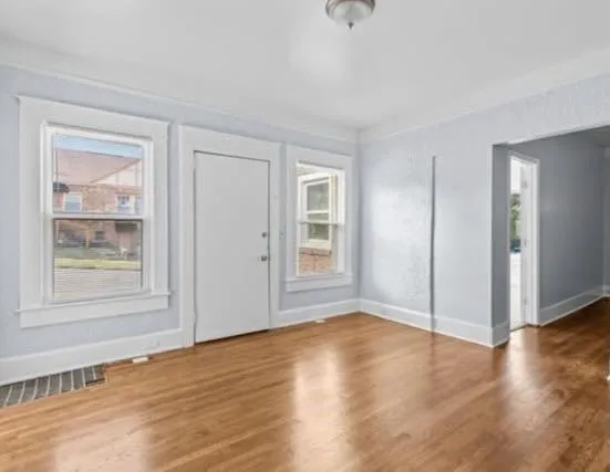 a view of an empty room with wooden floor and a window