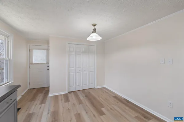 a view of an empty room with a window and wooden floor