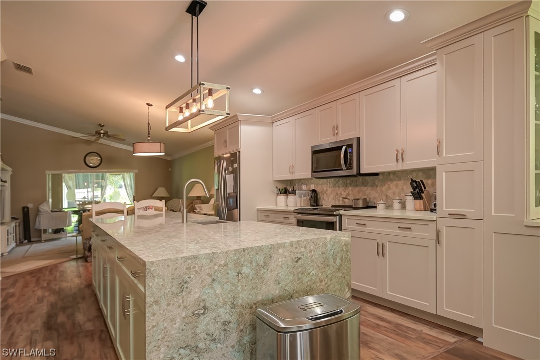 a kitchen with kitchen island granite countertop stainless steel appliances a sink stove and refrigerator