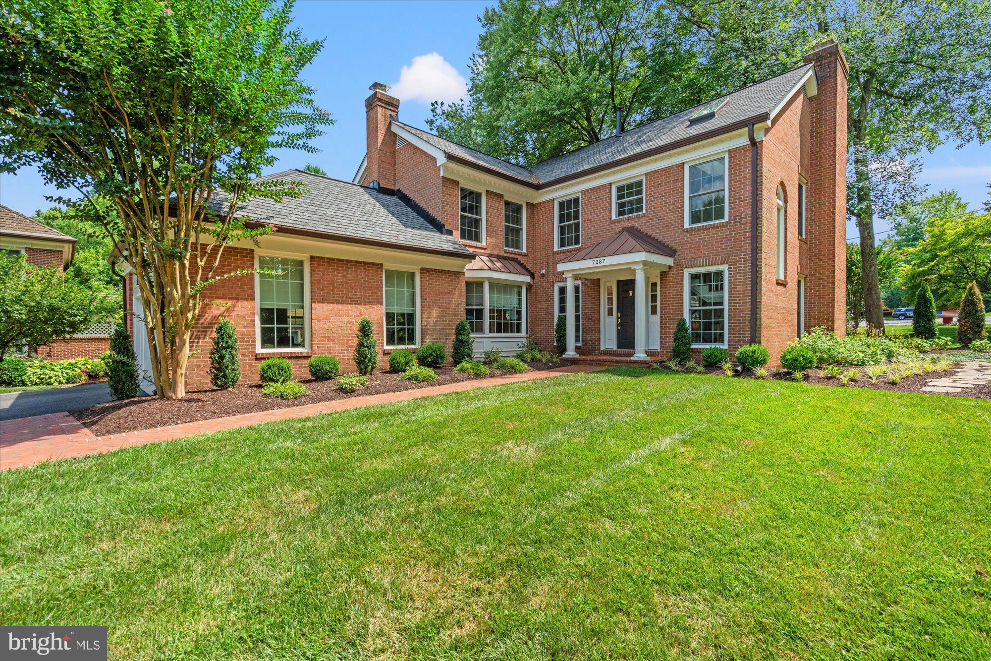 a front view of a house with a yard and trees