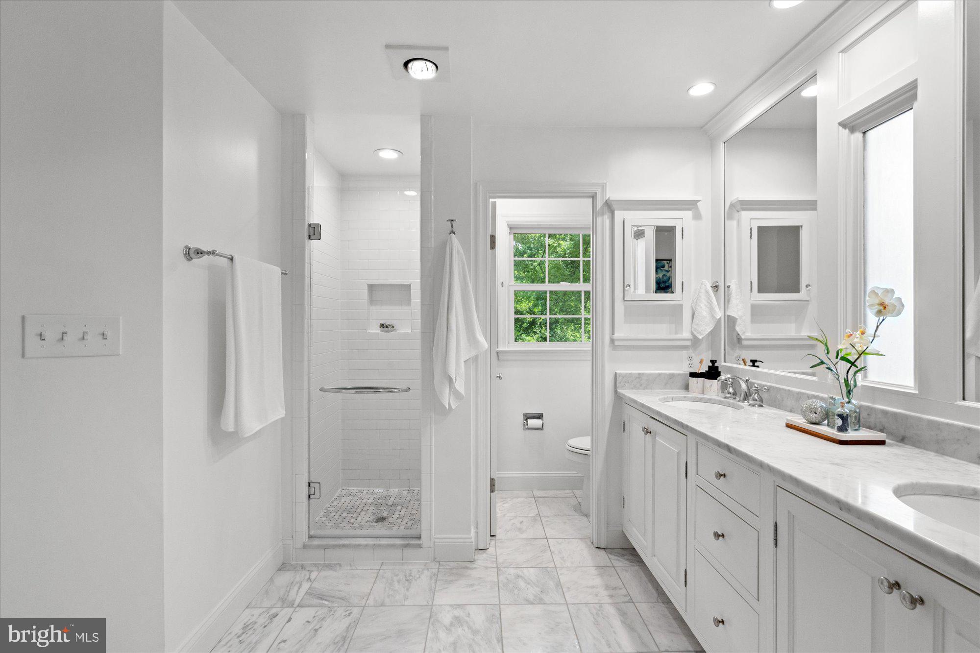 7287 Evans Mill Road McLean, VA 22101 - Photo 19 of 30 a bathroom with a granite countertop sink a large mirror a shower and a bathtub