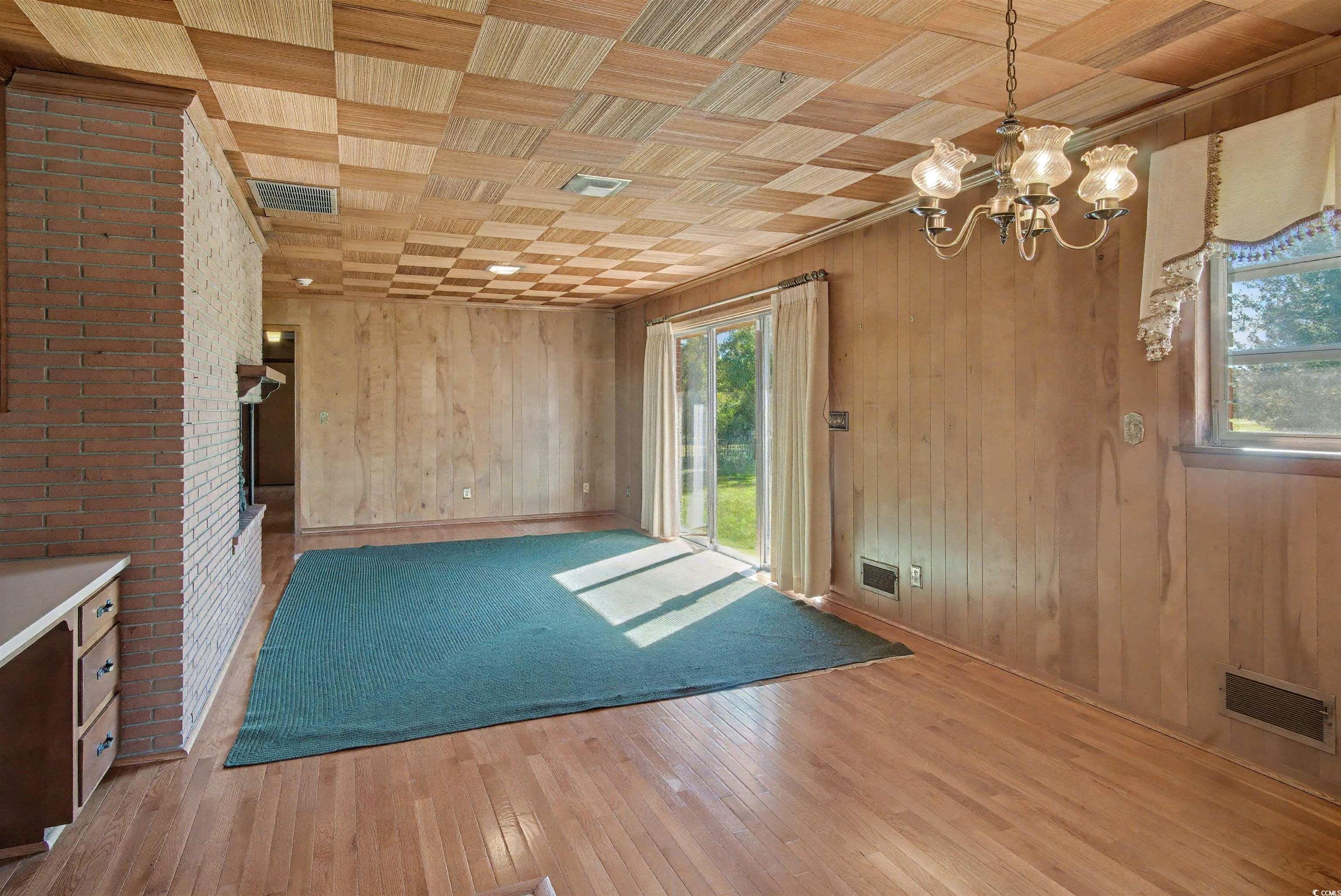 5408 Main Street Loris, SC 29569 - Photo 11 of 20 Unfurnished dining area with light wood-style floors, a chandelier, and wood walls