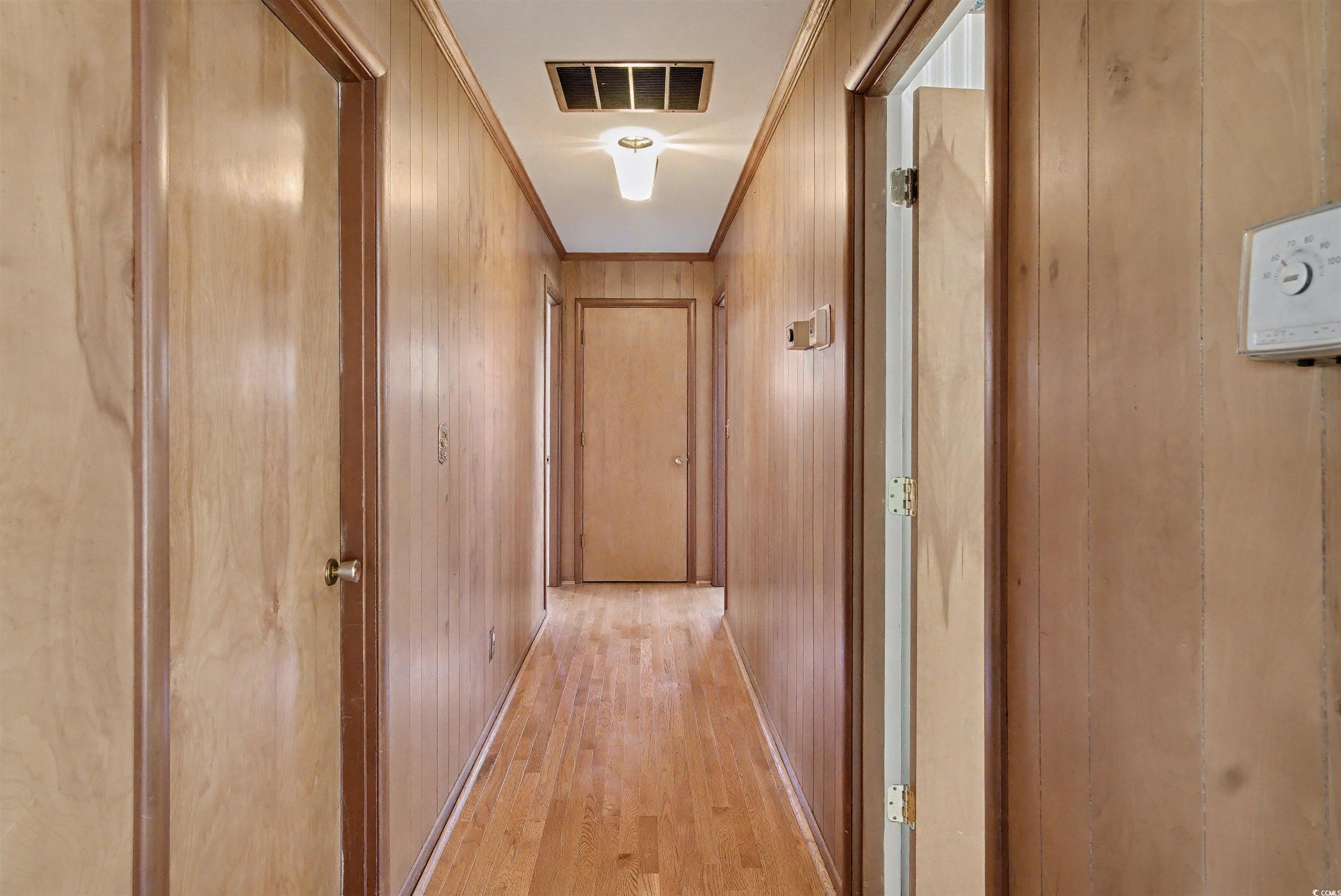 5408 Main Street Loris, SC 29569 - Photo 13 of 20 Hallway featuring crown molding, light wood-style floors, and wood walls