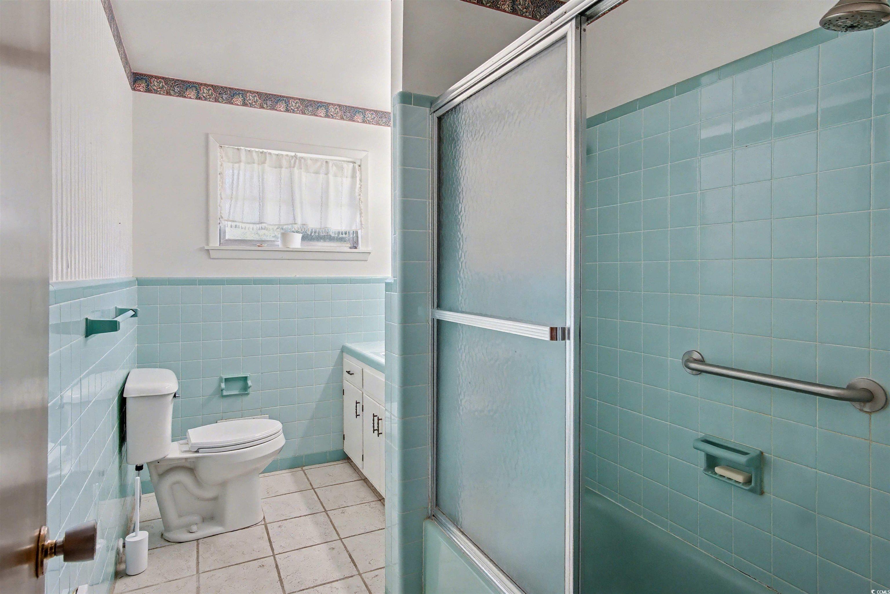 5408 Main Street Loris, SC 29569 - Photo 14 of 20 Full bathroom with combined bath / shower with glass door, light tile patterned floors, tile walls, a wainscoted wall, and vanity