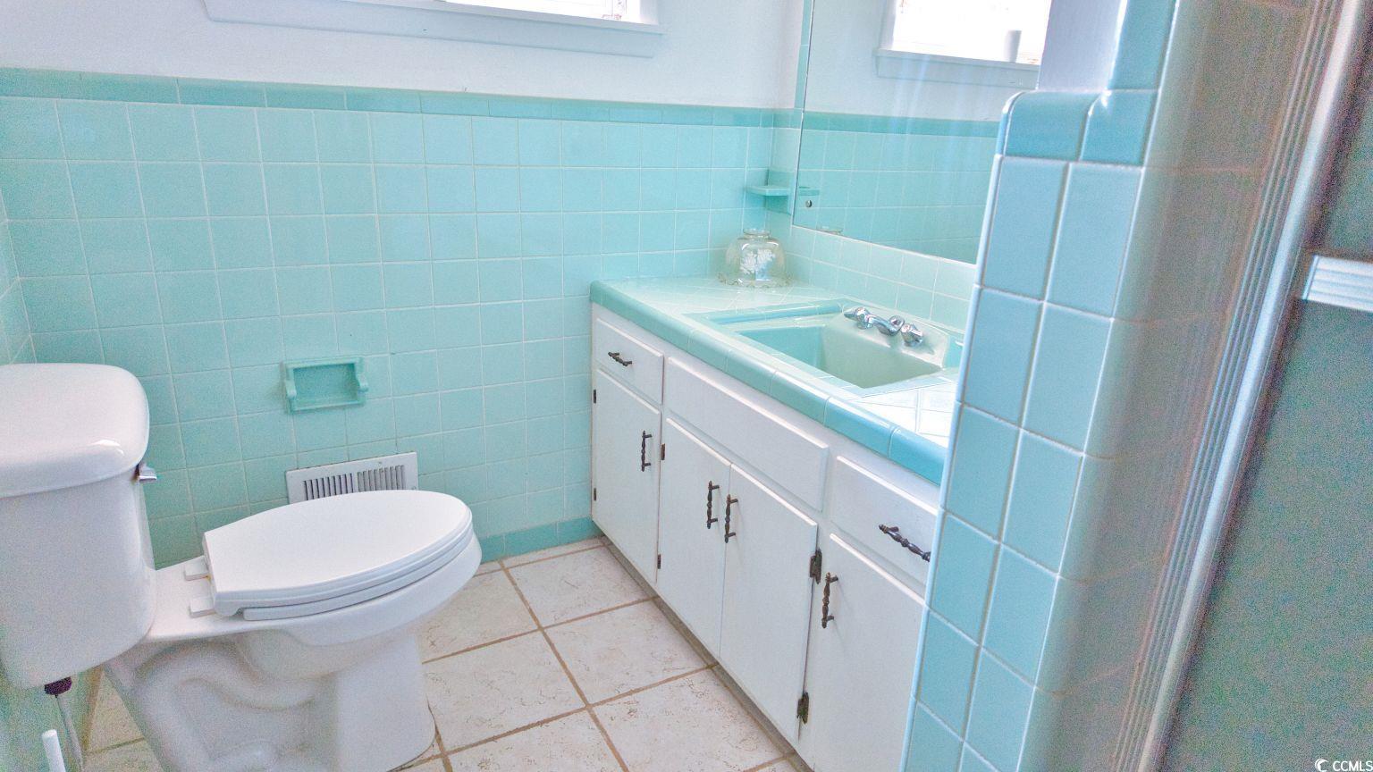 5408 Main Street Loris, SC 29569 - Photo 15 of 20 Bathroom featuring light tile patterned flooring, vanity, tile walls, and wainscoting
