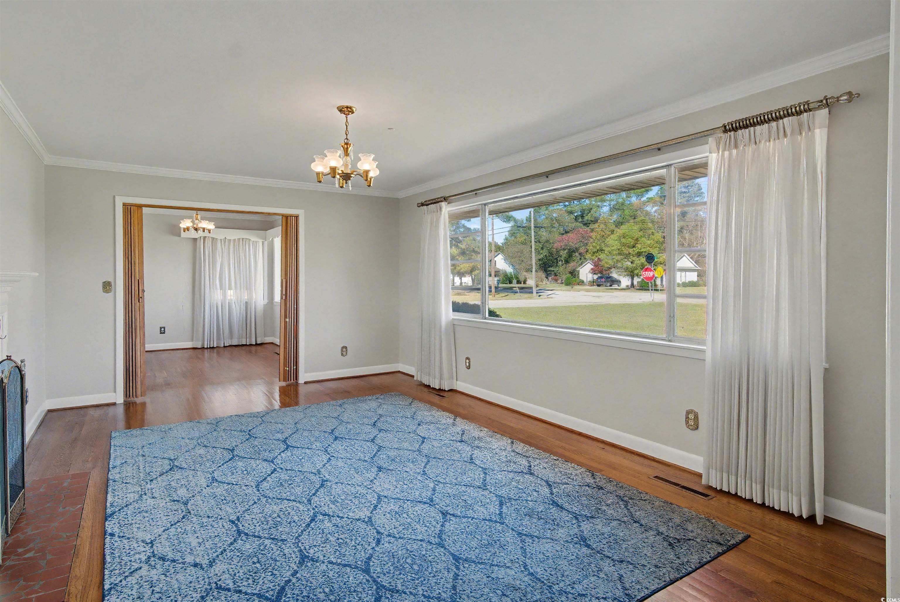 5408 Main Street Loris, SC 29569 - Photo 6 of 20 Unfurnished dining area featuring ornamental molding, dark wood-type flooring, a chandelier, and a fireplace