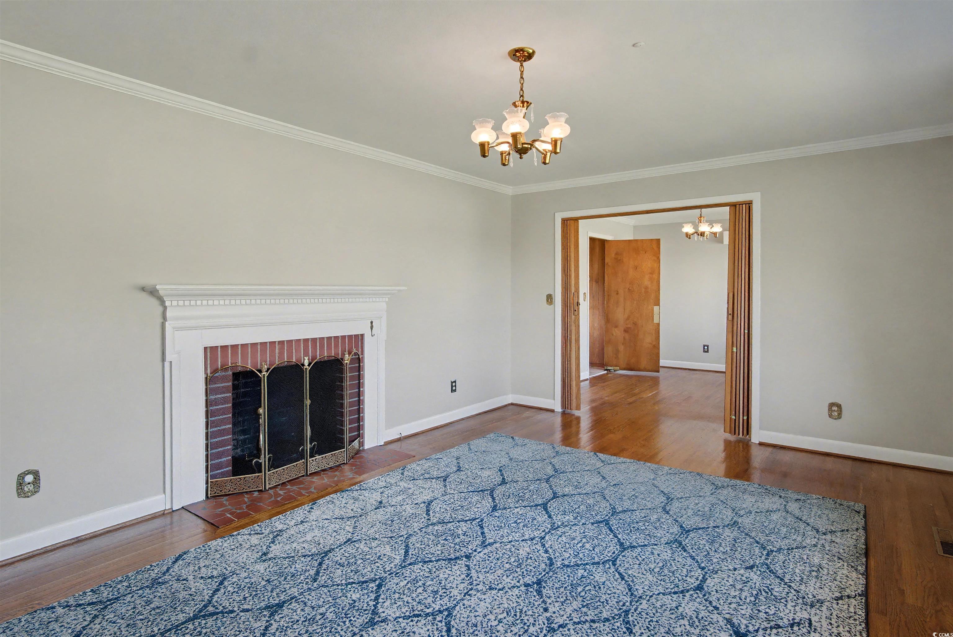 5408 Main Street Loris, SC 29569 - Photo 7 of 20 Living room with crown molding, a chandelier, dark wood-style floors, and a fireplace