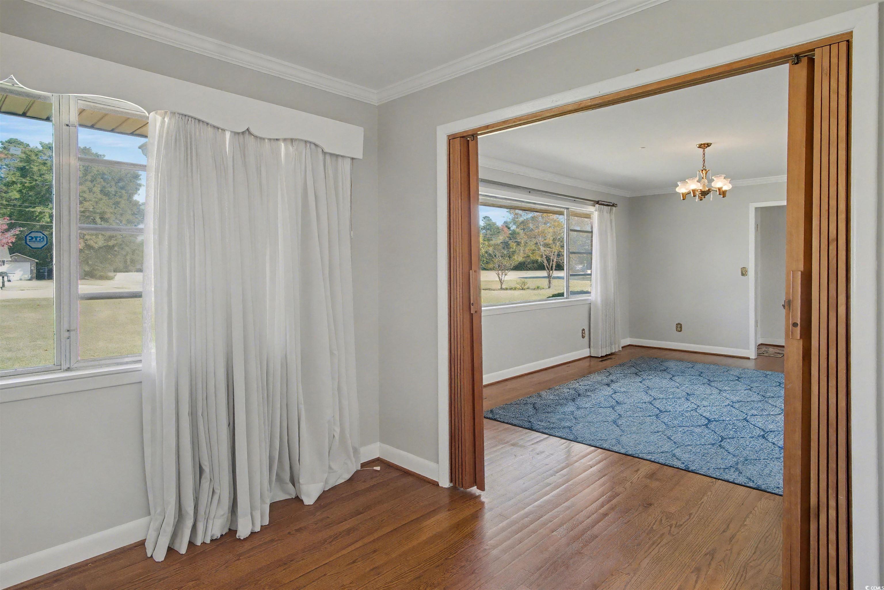 5408 Main Street Loris, SC 29569 - Photo 9 of 20 Spare room featuring ornamental molding, wood finished floors, and a chandelier