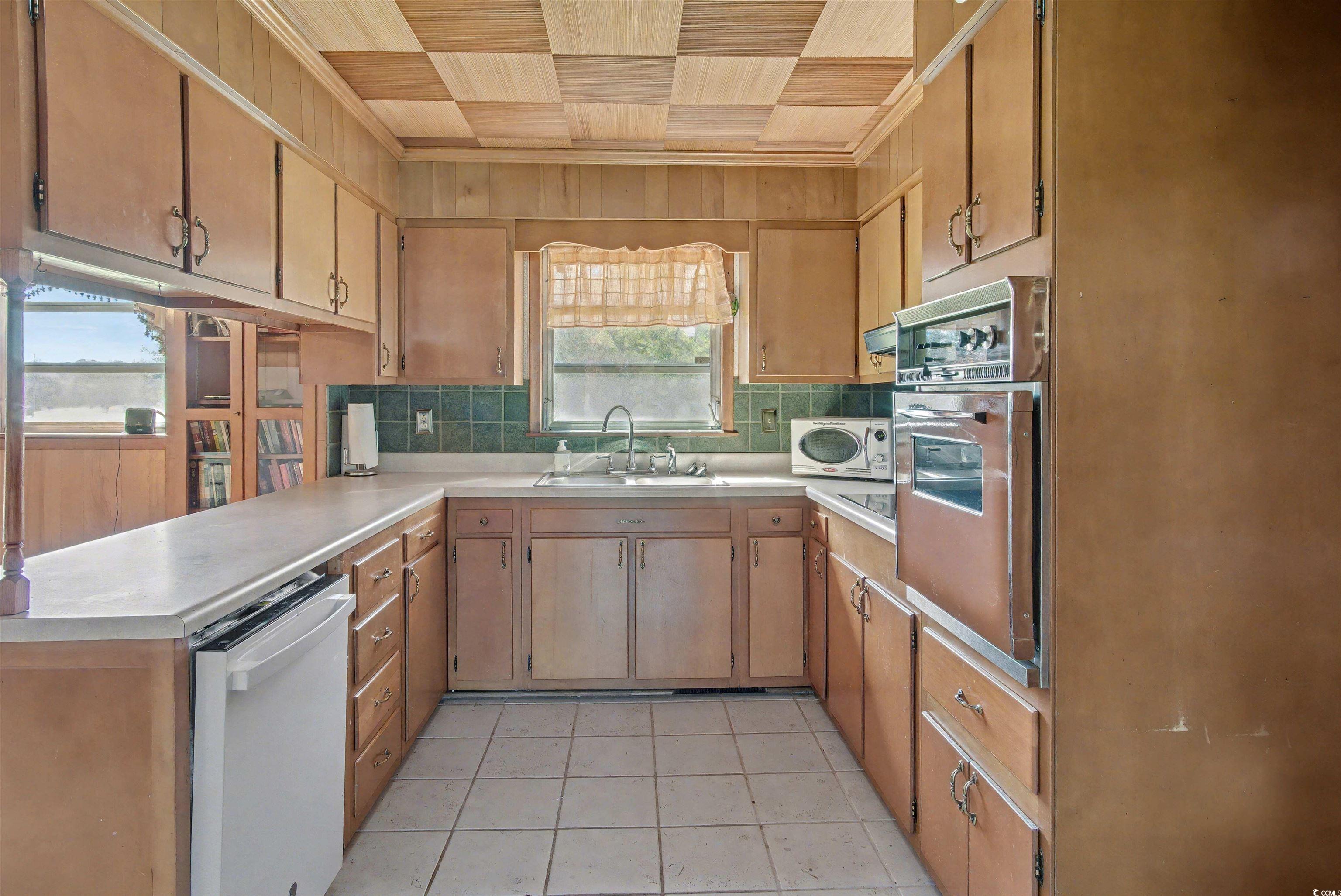 5408 Main Street Loris, SC 29569 - Photo 10 of 20 Kitchen featuring white appliances, light countertops, light tile patterned floors, a peninsula, and decorative backsplash