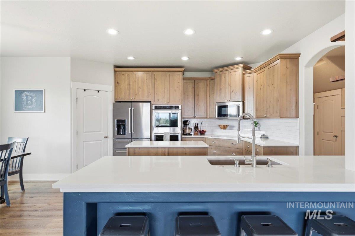 1282 Cimarron Court Middleton, ID 83644 - Photo 15 of 44 Kitchen with stainless steel appliances, a breakfast bar, light wood finish cabinetry, light stone counters, and recessed lighting