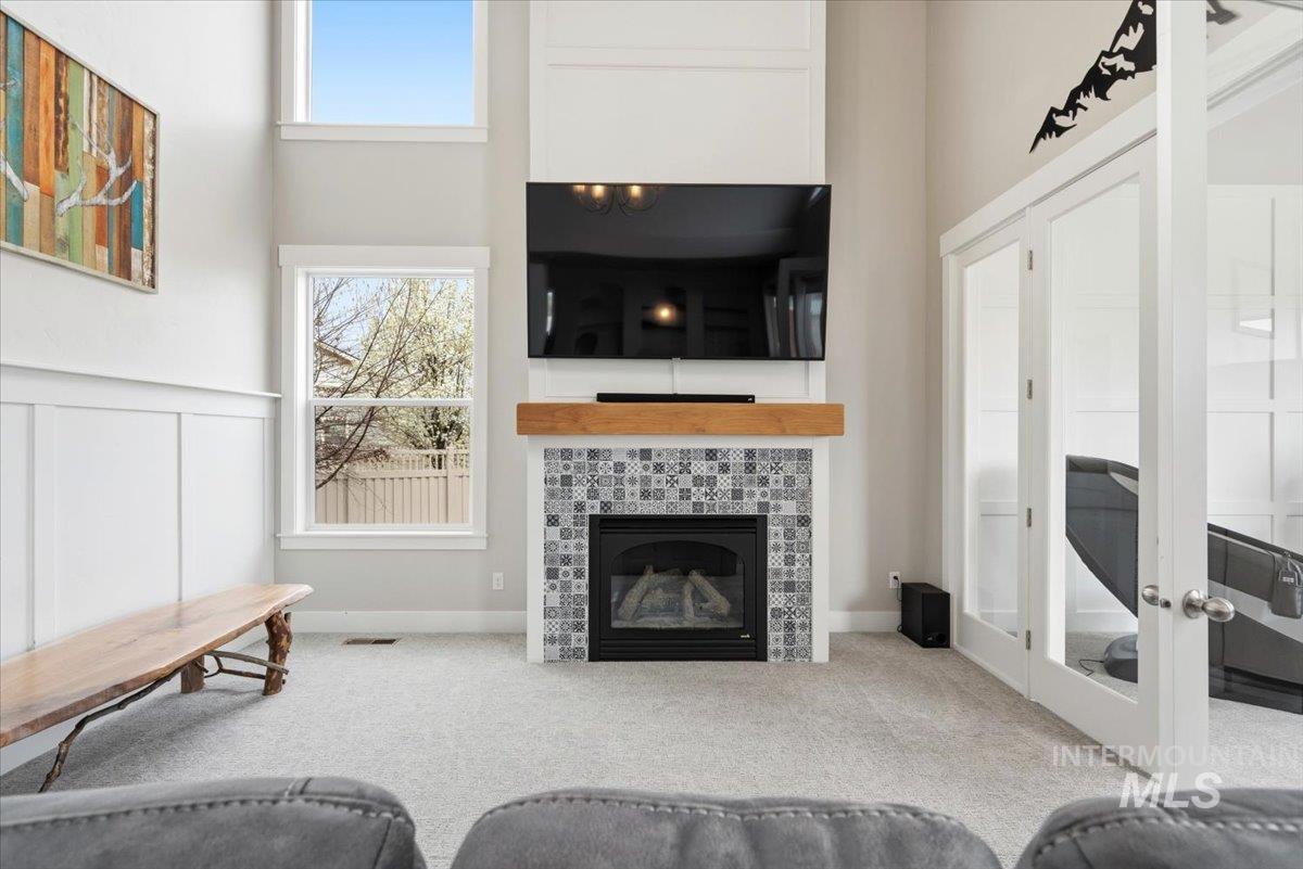 1282 Cimarron Court Middleton, ID 83644 - Photo 5 of 44 Carpeted living room with a high ceiling, a tiled fireplace, and a decorative wall