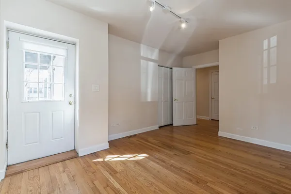a view of an empty room with wooden floor and a window