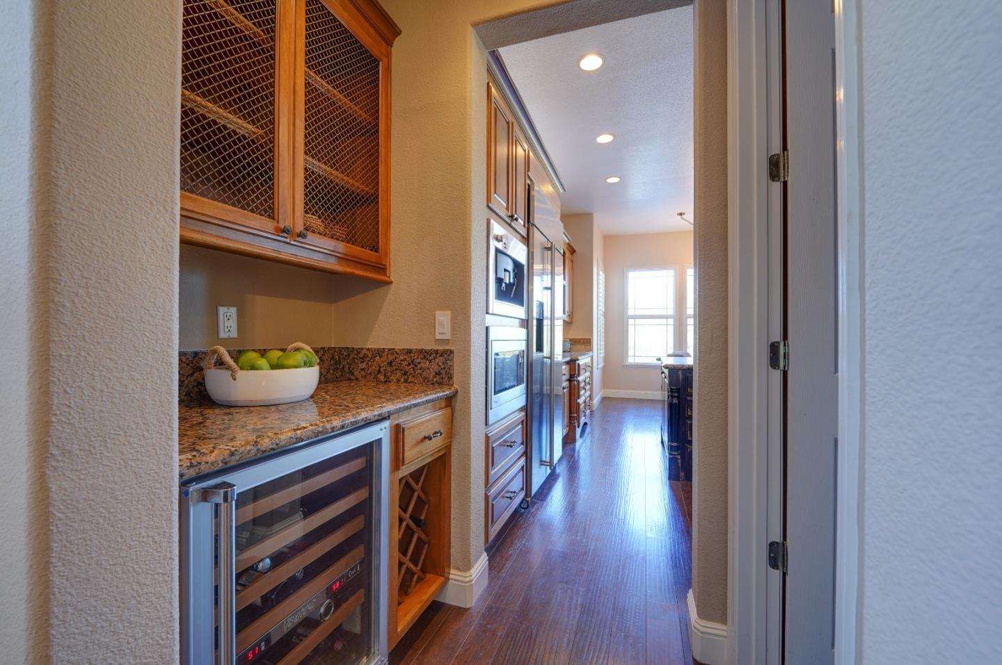 2400 Club Drive Gilroy, CA 95020 - Photo 16 of 67 a hallway with stainless steel appliances granite countertop a refrigerator and a wooden floor